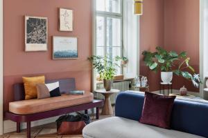 ジュネーヴにあるStay KooooK Geneva City - Online Check In NEW OPENINGのピンクの壁のリビングルーム(青いソファ付)