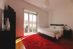 a bedroom with a large bed and a red rug at Boavista Sunlit Duplex with Terrace in Porto