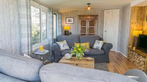 a living room with two couches and a tv at Easter Cabin in Moelfre