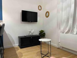 ein Wohnzimmer mit einem Tisch und einem TV an der Wand in der Unterkunft Appartement cosy proche du centre in Reims