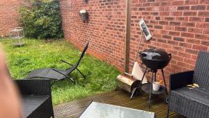 a grill and chairs on a deck with a brick wall at Benham in Parkside