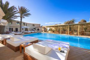 una piscina con tumbonas blancas y un complejo en Hotel Playa Sur Tenerife, en El Médano
