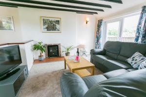 a living room with a couch and a tv at Dinas Cottage in Benllech
