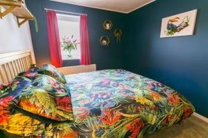 a bedroom with a bed with a colorful comforter at Dinas Cottage in Benllech