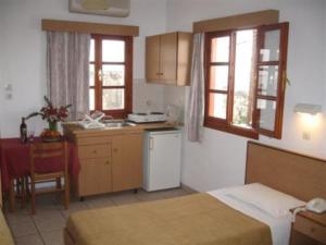 a kitchen with two beds and a kitchen with a table at Chrysa Studios in Lindos