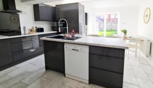 a kitchen with black and white cabinets and a sink at Spacious Semi - Off Street Parking - Central Crewe in Crewe