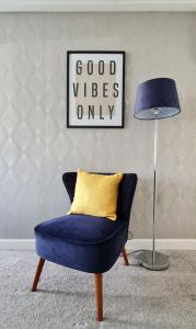 niebieskim krzesłem z żółtą poduszką obok lampy w obiekcie Spacious Semi - Off Street Parking - Central Crewe w mieście Crewe