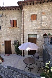 une table avec un parasol devant un bâtiment dans l'établissement Il Rustico di Meggiano, à Meggiano