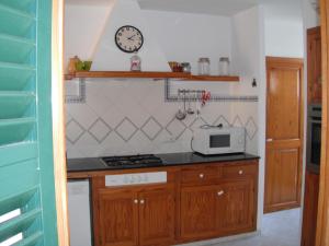 una cucina con piano cottura e orologio a muro di Casa familiar con piscina, cerca de la playa a Ciutadella