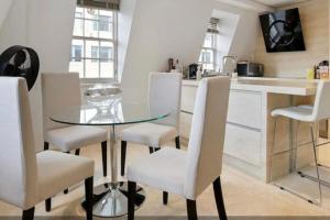 a kitchen with a glass table and white chairs at Mr Charing in London