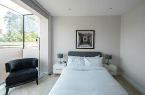 a bedroom with a bed and a chair at The Hampstead Hideout - Glamorous 3BDR Flat with Balcony in London
