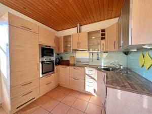 cocina grande con armarios de madera y fregadero en Ferienhaus Sonnenberg en Reith bei Seefeld