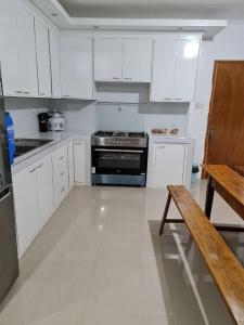 a kitchen with white cabinets and a stove and a bench at MoRue's Den in Mabini