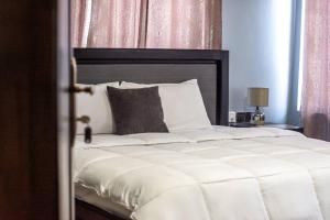 a bedroom with a large white bed with a black headboard at Afranasa Inn in Tema