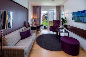 ein Wohnzimmer mit einem Sofa und lila Stühlen in der Unterkunft Hotel König Albert in Bad Elster