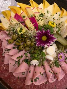 a plate of food with meat and cheese and flowers at Sapê Guest Hotel in Praia do Rosa