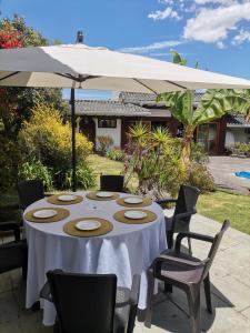 a table with chairs and an umbrella on a patio at La Granja de Papá Alberto in Puembo