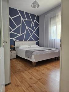 1 dormitorio con cama y pared azul en Titi's home Velipoje en Velipojë