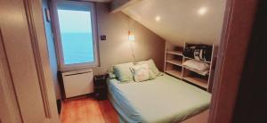 Un dormitorio pequeño con una cama y una ventana. en Bellerive, pieds dans l'eau lac & montagnes, en Publier