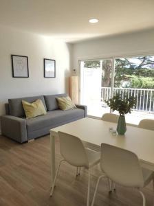 Una sala de estar con un sofá, una mesa y sillas. en Apartamento Reformado con Aparcamiento. Playa 5min a pie., en Platja d'Aro