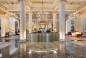 a lobby with columns and a person sitting at a desk at Grand Hotel Et Des Palmes in Palermo