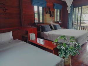 a bedroom with two beds and a potted plant at Suntisook Resort in Ko Yao Noi