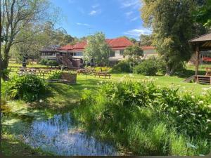 a park with benches and a pond in the grass at Eversprings Glamping in Mount Helena
