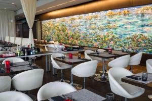 ケルンにあるart'otel cologne, Powered by Radisson Hotelsの大絵の前のテーブルと椅子のあるレストラン