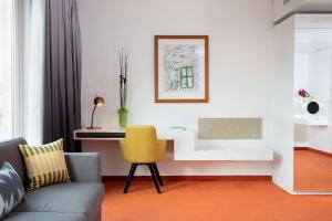 uma sala de estar com um sofá e uma cadeira amarela em art'otel berlin mitte, Powered by Radisson Hotels em Berlim