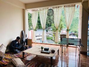 a man sitting on a couch in a living room at Rahgir Mcleodganj in McLeod Ganj