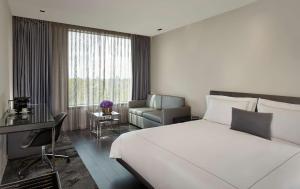 um quarto com uma grande cama branca e uma cadeira em Park Plaza London, Park Royal em Londres