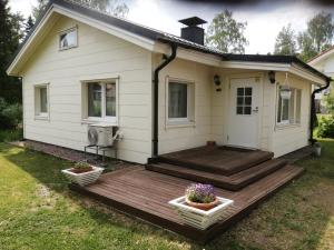 a small white house with a wooden deck at Sosa's villa. (Free Coffee, BBQ & Garden Fruits) in Turku
