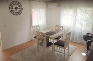 einen Tisch und Stühle in einem Zimmer mit einer Uhr an der Wand in der Unterkunft Sosa's villa. (Free Coffee, BBQ & Garden Fruits) in Turku