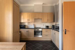 a kitchen with wooden cabinets and a stove top oven at Stunning 2BR, 2BA, Apartment - Super King Size Beds - Free Parking - 6 mins to LGW Airport in Crawley