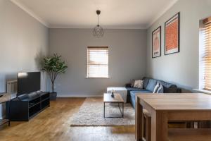 a living room with a blue couch and a table at Stunning 2BR, 2BA, Apartment - Super King Size Beds - Free Parking - 6 mins to LGW Airport in Crawley