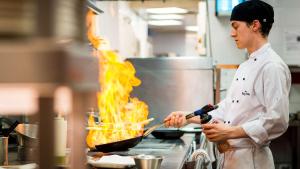 a chef cooking food in a wok in a kitchen at Park Plaza London Westminster Bridge in London
