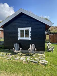 two chairs sitting in front of a blue house at Osetunet, small and charming cabin at Ustaoset in Ustaoset