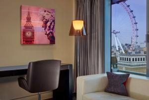 a hotel room with a chair and a desk and a large window at Park Plaza London Westminster Bridge in London