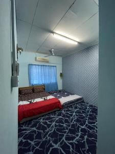 - une chambre avec un grand lit et une couverture rouge dans l'établissement ZZR Homestay, à Kampong Tanah Merah