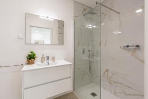 a white bathroom with a sink and a shower at Villa Patricia in Santa Barbara +32 photos