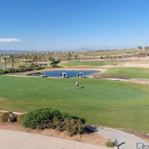 a golf course with a lake and a golfer on a green at Un Oasis en Hacienda del Álamo in Murcia
