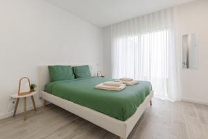 a white bedroom with a green bed and a window at Villa Patricia in Santa Barbara