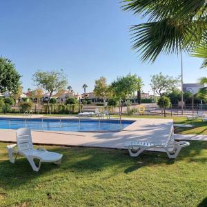 two chairs and a bed next to a swimming pool at Un Oasis en Hacienda del Álamo in Murcia