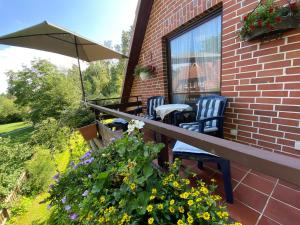 eine Terrasse mit 2 Stühlen, einem Sonnenschirm und Blumen in der Unterkunft Gästezimmer Neumair in Undeloh