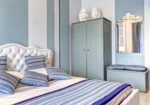 una camera da letto con un letto con pareti blu e uno specchio di SuiteHome Taormina a Giardini Naxos