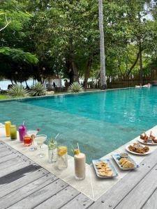 a table with food and drinks next to a swimming pool at Amahelia Luxury Resort & Restaurant - Gili Asahan in Gili Asahan