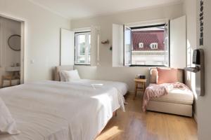 a white bedroom with a bed and a chair at Lisbon Story Guesthouse in Lisbon