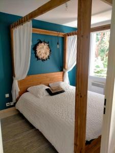 een slaapkamer met een houten hemelbed en een raam bij L'Eucalyptus in Marans