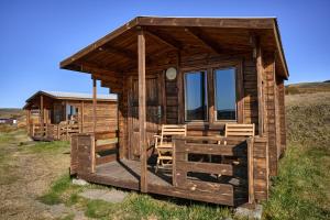 uma cabina de madeira com cadeiras num campo em Hlíd Huts em Myvatn