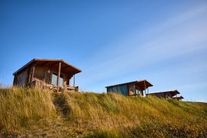 Tres cabañas de madera en la cima de una colina de hierba en Hlíd Huts en Myvatn